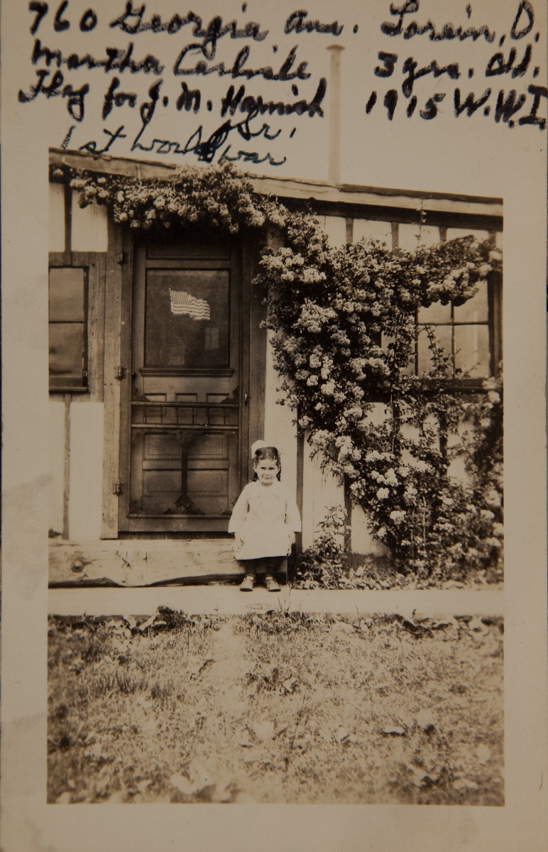1915 WW1, Martha Carlisle 3yr old, flag on door for J.M.Harnish Sr, first world war. , home  at 760 Georgia Ave", covered with roses.