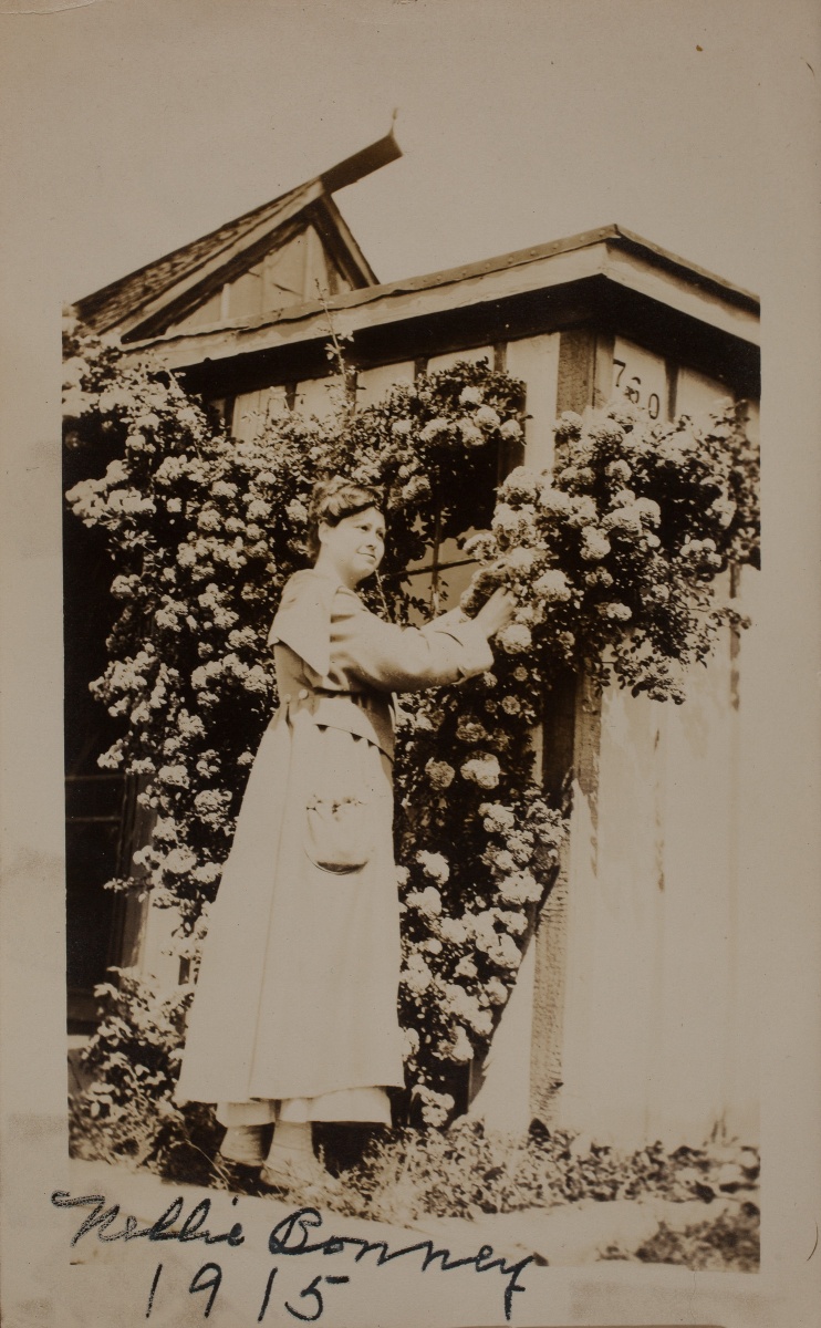 1915 Nellie Bonney" at 760 Georgia home tending roses covering front of house, note house numbers above roses.