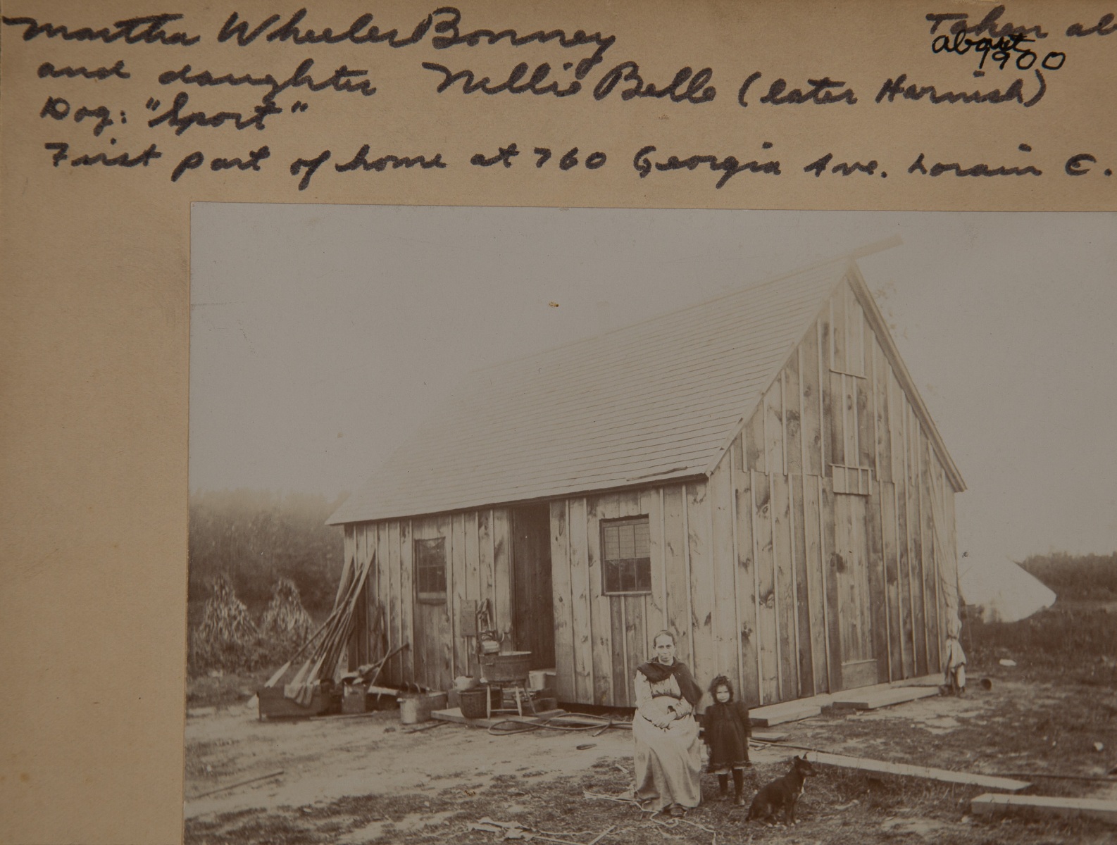 1900, "Taken about 1900, Martha Wheeler Bonney and daughter Nellie Belle (later Harnish), Dog: "Sport", First part of home at 760 Georgia Ave. Lorain, O." labeled by John Malcolm, note written by Nellie B Harnish "Nellie B, dog Sport and Mother Martha Jane Bonney, first part of home built 1899 taken about 1900 "